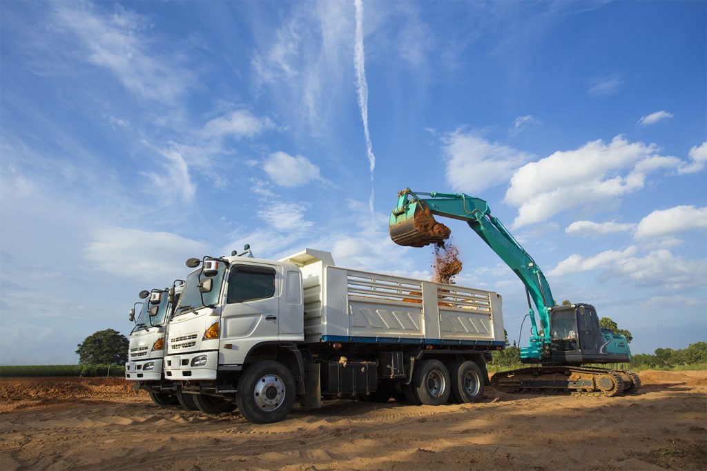 Hino dump truck being loaded by an excavator on a construction site